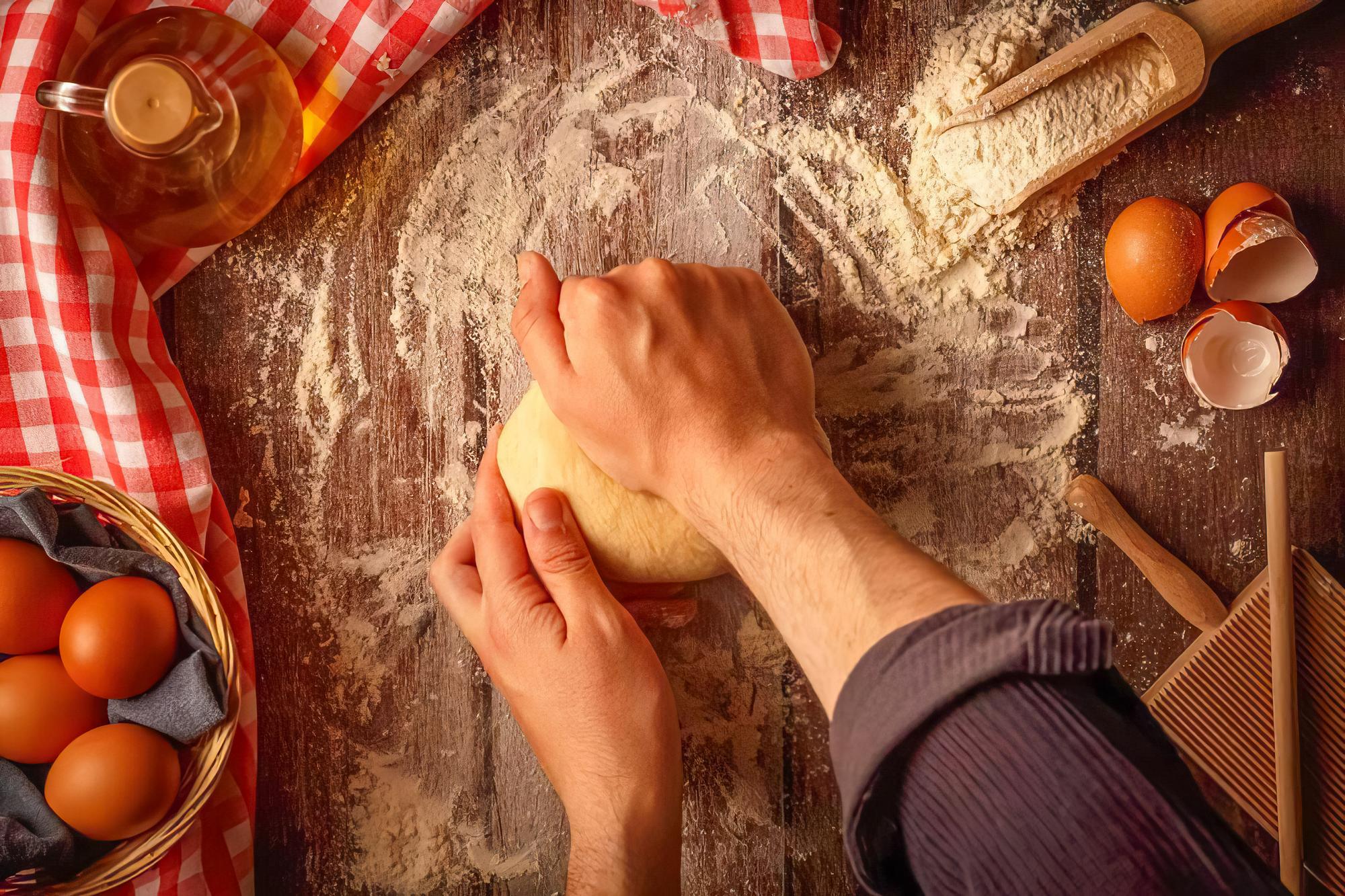 Hands kneading dough on wooden surface